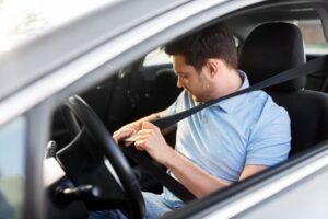 man fastening seat belt in car