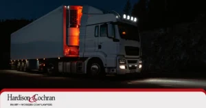A commercial truck driving on a Raleigh highway at night, representing the dangers of truck driver fatigue accidents