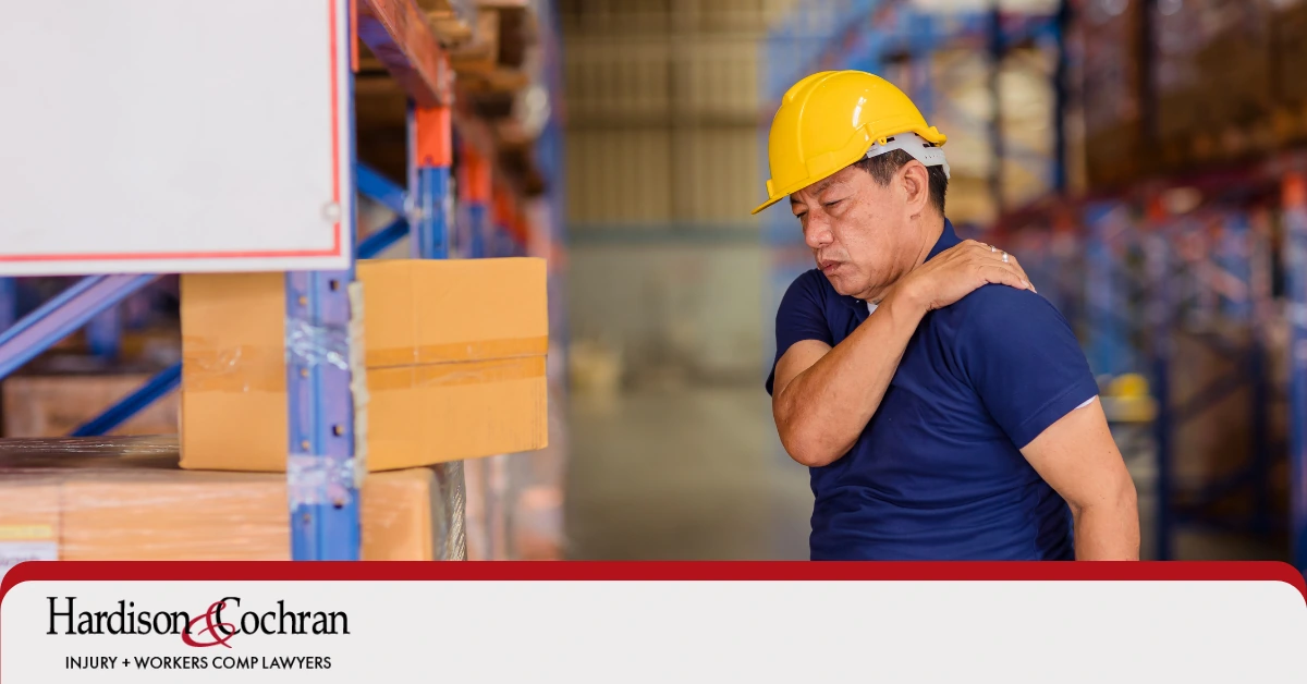 A worker holds their shoulder in pain at a warehouse job site in Greensboro, NC.